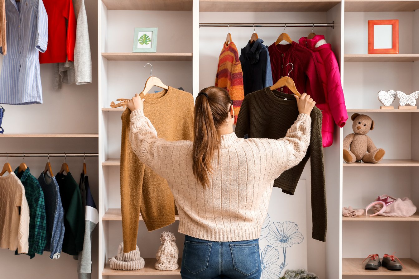 Woman Choosing Winter Clothes near Wardrobe